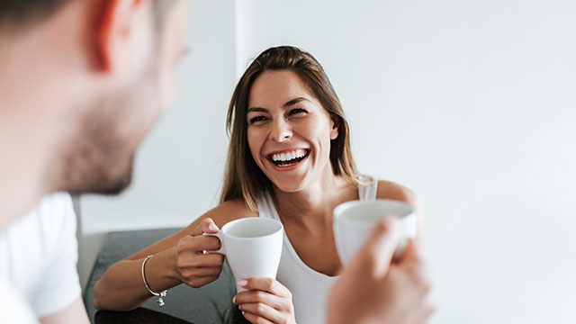 Mujer y hombre sosteniendo tazas mientras sonrien