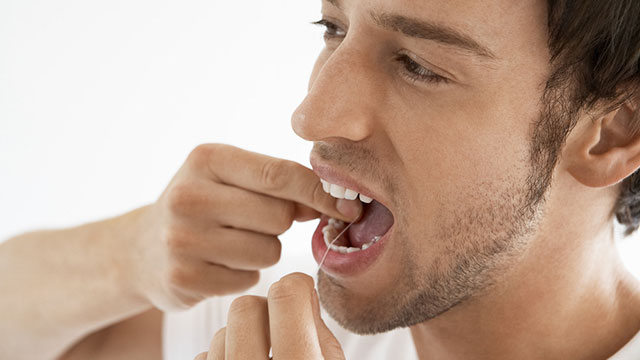 un hombre adulto usando hilo dental