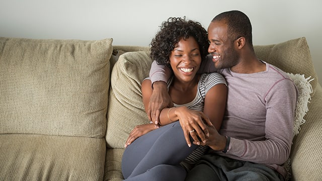 Pareja feliz sonriendo sentada en un sofá